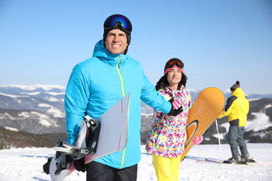 Couple with snowboards at ski resort. Winter vacation