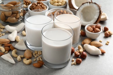 Vegan milk and different nuts on grey table