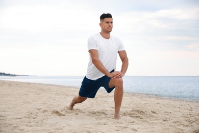 Muscular man doing exercise on beach. Body training