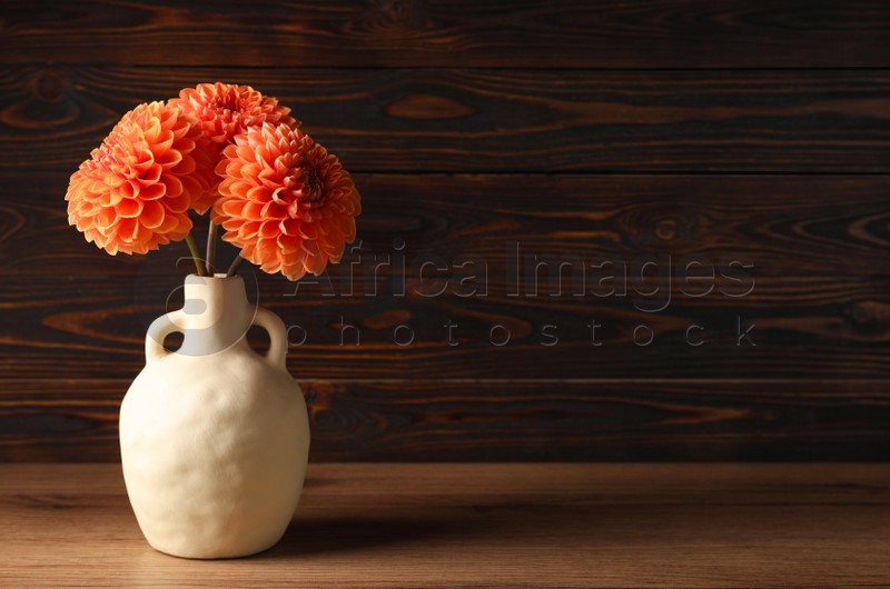 Beautiful flowers in vase on wooden table, space for text