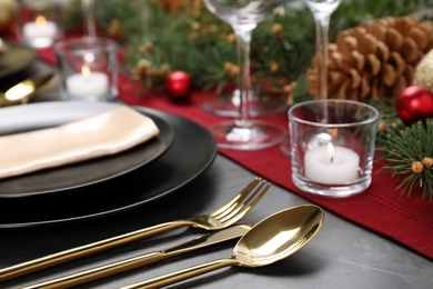 Christmas table setting with plates, cutlery, napkin and festive decor on grey background, closeup