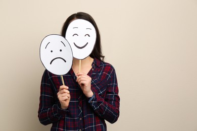 Woman with sad and happy paper faces on beige background. Space for text