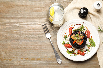Photo of Delicious black risotto with seafood served on wooden table. Space for text