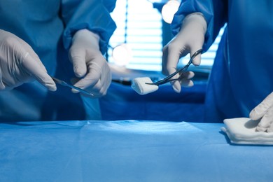 Professional surgeons with instruments performing operation in clinic, closeup