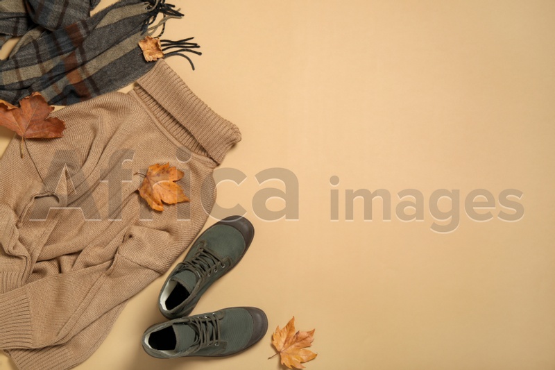 Photo of Flat lay composition with sweater and dry leaves on beige background, space for text. Autumn season