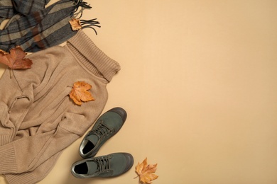 Flat lay composition with sweater and dry leaves on beige background, space for text. Autumn season