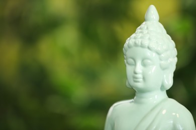 Buddha statue against blurred green background, closeup. Space for text