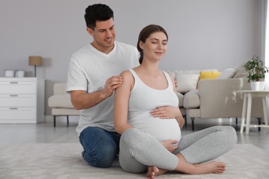 Photo of Husband massaging his pregnant wife in living room. Preparation for child birth