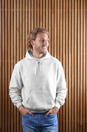 Photo of Portrait of man in hoodie sweater on wooden background. Space for design