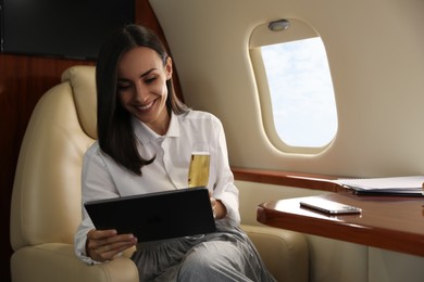 Woman with tablet and glass of champagne in airplane during flight