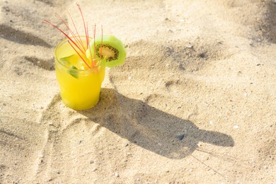 Glass of refreshing drink with kiwi and mint on sand. Space for text