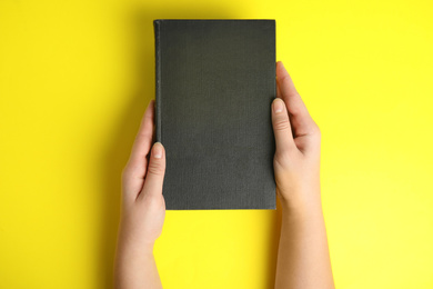 Woman with book on yellow background, top view. Space for design