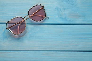 New stylish sunglasses on turquoise wooden table, top view. Space for text