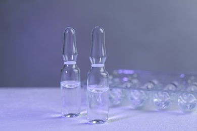 Pharmaceutical ampoules with medication on white table against grey background