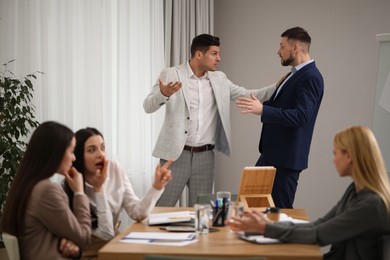 Photo of Angry coworkers quarreling at workplace in office