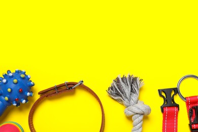Flat lay composition with dog collar and toys on yellow background. Space for text