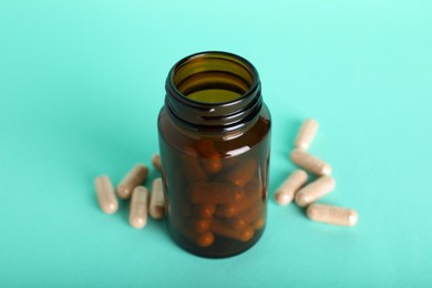 Gelatin capsules and bottle on turquoise background, closeup