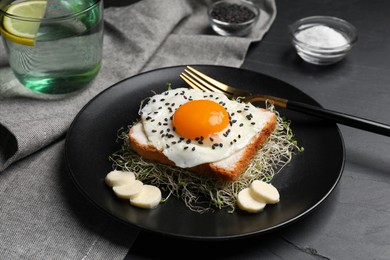 Tasty toast served with egg, cheese and microgreens on black table