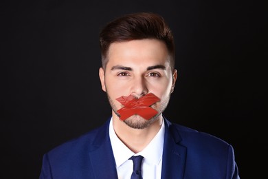Man with taped mouth on black background. Speech censorship