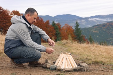 Man making bonfire in mountains. Camping season