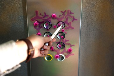Woman using pen press button in elevator with germs, closeup