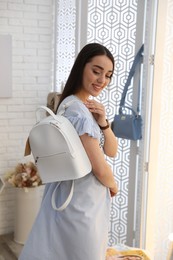 Photo of Woman wearing stylish dress and choosing backpack in showroom