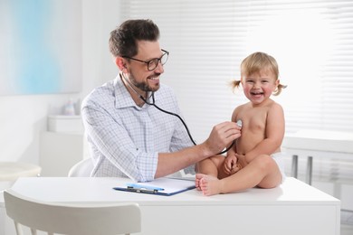 Pediatrician examining baby with stethoscope in clinic