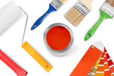 Can of orange dye, paint chips, roller and brushes on white background, top view