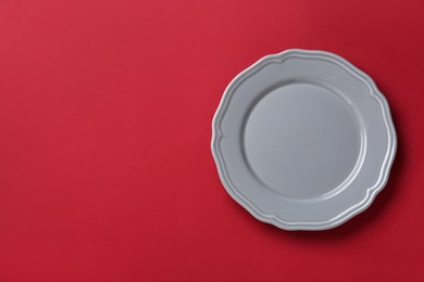 Clean grey plate on red background, top view. Space for text
