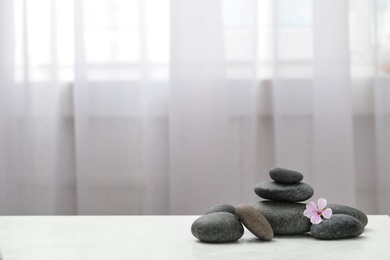 Photo of Spa stones and fresia flower on white table indoors. Space for text