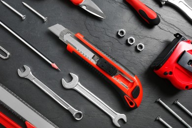 Photo of Flat lay composition with utility knife and different tools on black table