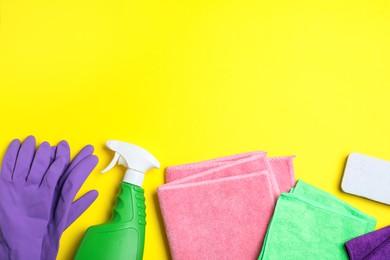 Photo of Microfiber cloths and cleaning supplies on yellow background, flat lay. Space for text