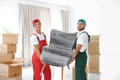 Male movers carrying armchair in new house