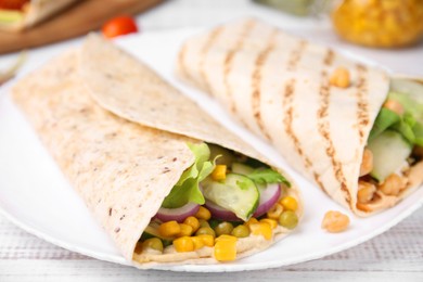 Photo of Delicious hummus wraps with vegetables on table, closeup