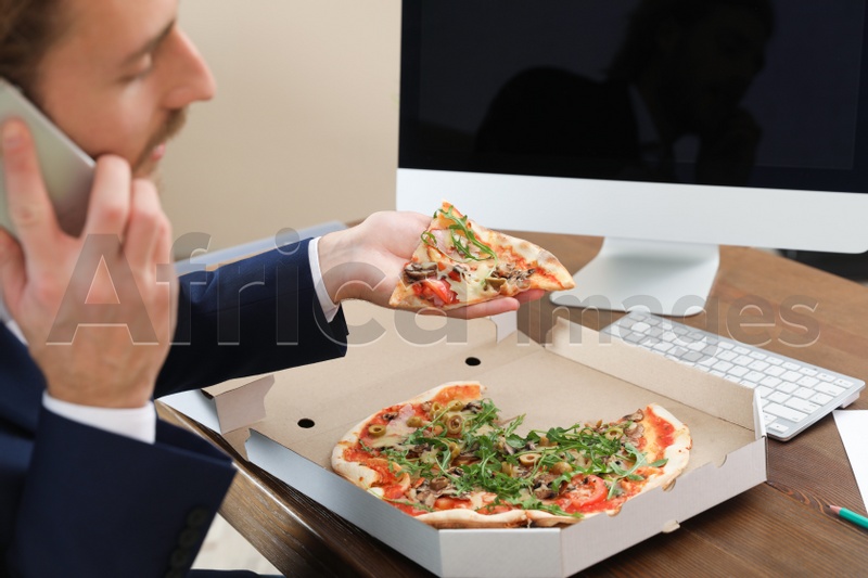 Office employee having pizza for lunch at workplace, closeup. Food delivery