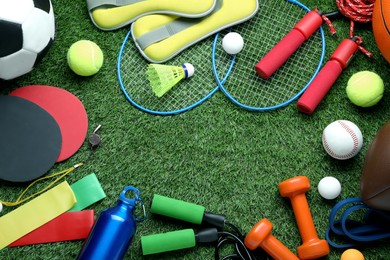 Photo of Set of different colorful sports equipment on green grass, flat lay. Space for text