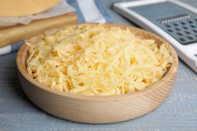 Tasty grated cheese on light grey wooden table