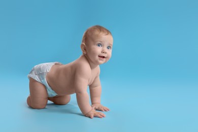 Cute baby in dry soft diaper crawling on light blue background. Space for text