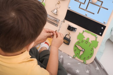 Little boy playing with busy board on bed