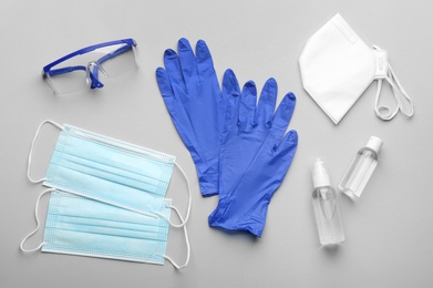 Flat lay composition with medical gloves, masks and hand sanitizers on grey background