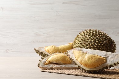 Fresh ripe durians on light wooden table. Space for text
