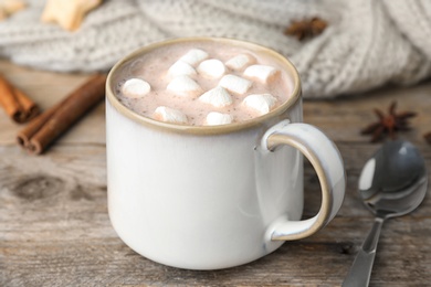 Delicious hot cocoa drink with marshmallows in cup on wooden table, closeup