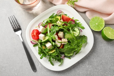 Delicious salad with feta cheese, arugula and vegetables on grey table, flat lay