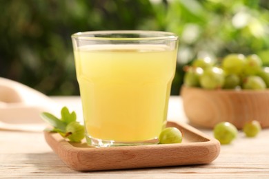 Photo of Tasty gooseberry juice and fresh berries on wooden table