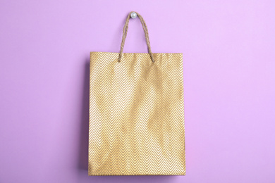 Gold shopping paper bag on violet background
