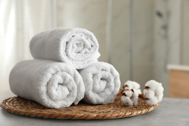Clean rolled towels and cotton flowers on table in bathroom