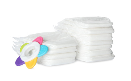 Disposable diapers and teether on white background