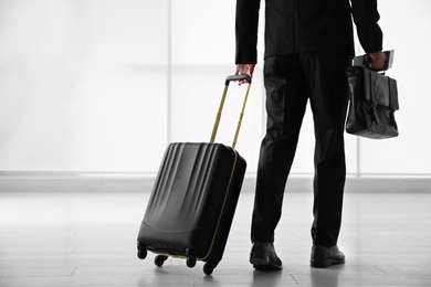 Businessman with black travel suitcase in airport
