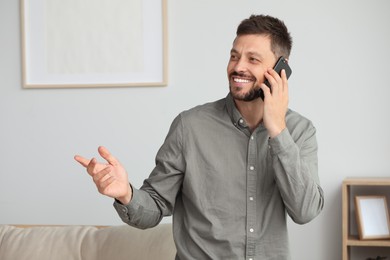 Happy man talking on smartphone at home