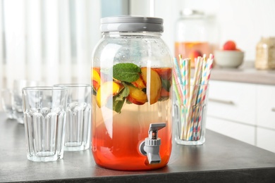 Peach cocktail in jar with tap on table. Refreshing drink